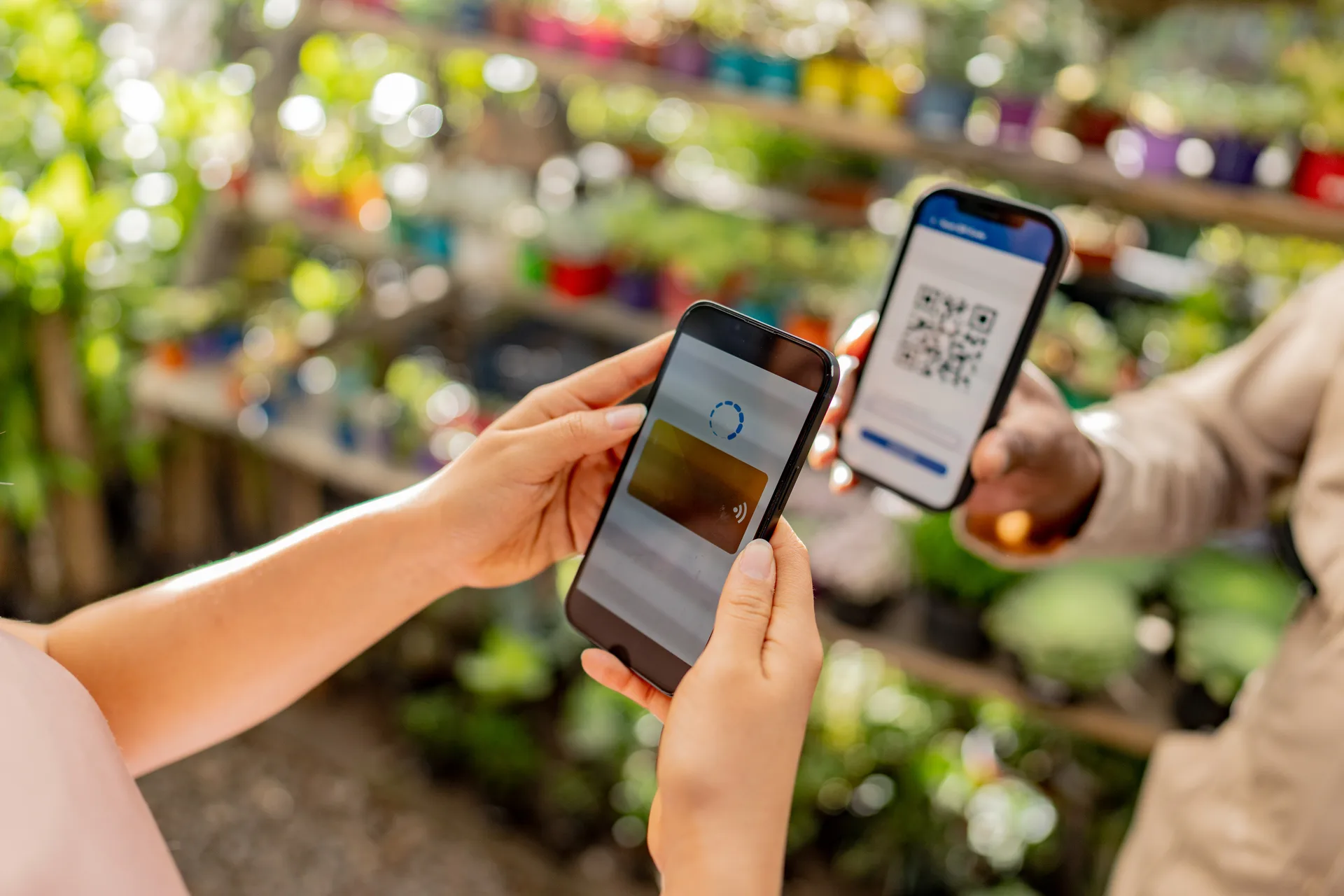 A vendor holding up a phone showing a QR code while a customer scans it to pay at a market stall